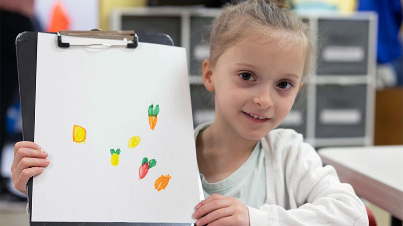Image of a young girl displaying her artwork